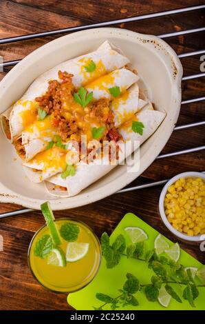 Carni cotte al forno tortilla con il formaggio cheddar, peperoncino e mais, drink di lime Foto Stock