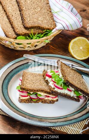 Snack sani - pane integrale con uovo-crema diffusione e verdure fresche foglie di rucola e ravanelli Foto Stock