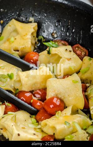 Tortellini fatti in casa da farina di semola, ripiene di formaggio parmigiano e pomodori Foto Stock