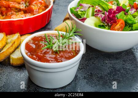 Hot ali di pollo con il piccante salsa habanero e insalata mista con pomodorini e grigliate di baguette con olio d'oliva Foto Stock