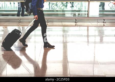 Viaggiatore che tira valigia nel moderno terminal aeroportuale Foto Stock