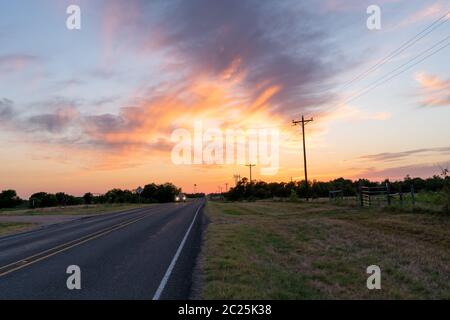 Auto che arriva verso la fotocamera in un grandangolo di tramonto Hill Country Foto Stock