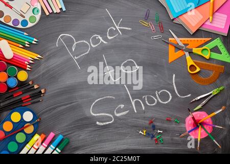 Accessori di cancelleria sullo sfondo della lavagna con iscrizione: Torna a scuola. Vista dall'alto. Accessori scolastici per l'istruzione dei bambini e. Foto Stock