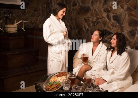 Cerimonia del tè dopo la sauna. Le ragazze in cappotti bianchi bevono tè cinese. Foto Stock