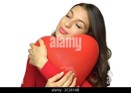 Attraente giovane donna che tiene il pallone d'aria rosso del cuore con gli occhi chiusi su sfondo bianco. Concetto di San Valentino. Spazio di copia. Foto Stock