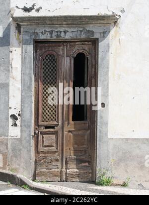 e vecchio elegante porta marrone in legno ornato con intagli e griglia mancante in una casa bianca abbandonata Foto Stock