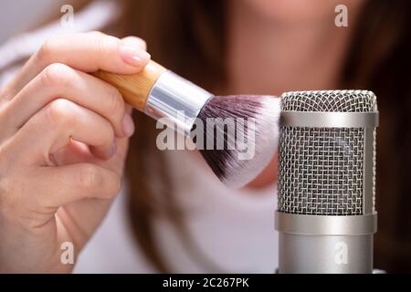 Donna che utilizza la spazzola sul microfono per rendere i suoni ASMR Foto Stock