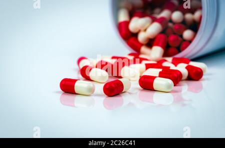 Rosso-bianco capsula pillole sul tavolo bianco su sfondo sfocato del flacone di farmaco. Antibiotici la resistenza al farmaco. Capsula di antimicrobici pillole. Prodotti farmaceutici Foto Stock
