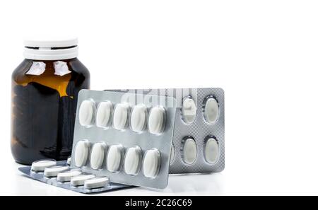 Macro shot di vitamine capsula in vetro ambrato con etichetta vuota e supplementi compresse in blister su sfondo bianco. Antiossidanti per lui Foto Stock