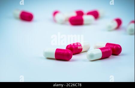 Rosa-bianco pillola della capsula sulla capsula sfocata sullo sfondo. Farmaco antibiotico resistenza. Capsula di antimicrobici pillole. Farmacia farmacia. Ind farmaceutica Foto Stock