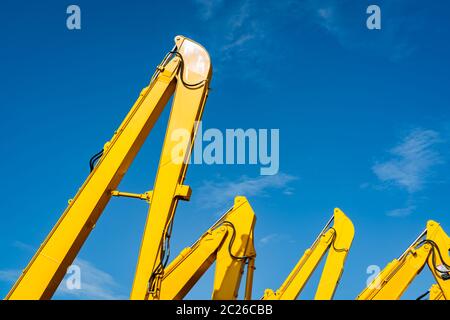 Giallo retroescavatore con pistone idraulico braccio contro il cielo blu e chiaro. Macchina pesante per lo scavo nel sito in costruzione. Macchine idrauliche. Enorme infrangere Foto Stock