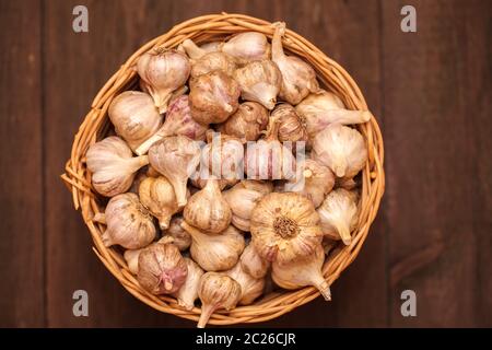 teste di aglio in un cesto di vimini su un legno Foto Stock