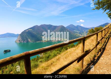 Recinzione in primo piano con vista panoramica del lago di montagna con isola in mezzo. Panorama dal Monte Isola isola con il lago d'Iseo, Italia. Foto Stock