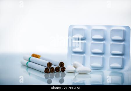 La nicotina chewing gum in confezione blister vicino a pila di sigaretta. Smettere di fumare da utilizzare la gomma alla nicotina per il sollievo di nicotina i sintomi di astinenza. Medicina per Foto Stock