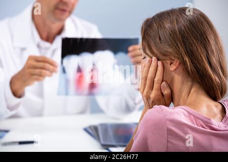 Donna con Dente dolore seduto di fronte medico controllo apparecchiature odontoiatriche a raggi X Foto Stock