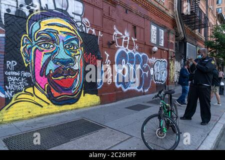 New York, NY - 16 giugno 2020: Un uomo scatta foto del murale di George Floyd ucciso da un ufficiale di polizia visto in un angolo di Houston Street e Bowery Foto Stock