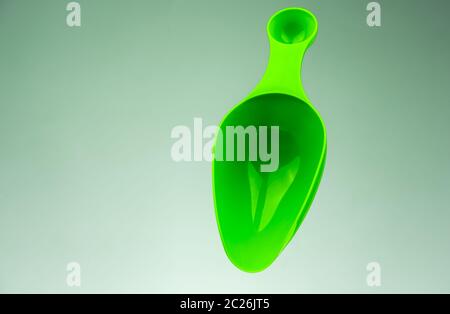 Green cucchiaino dosatore in plastica isolato sul gradiente grigio-bianco sfondo con copia spazio. Foto Stock