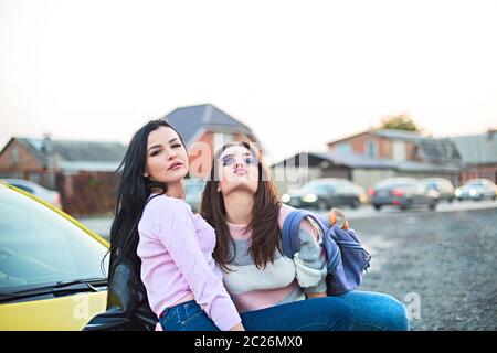 Le migliori amiche che si acclamano in auto viaggio su strada al tramonto. Happy People all'aperto in vacanza tour Foto Stock