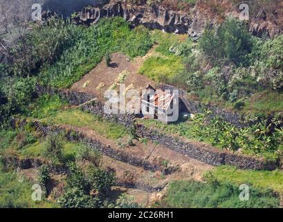 vista aerea di una cascina abbandonata in rovina circondata da campi terrazzati murati tipici di un antico agricolo in scala ridotta Foto Stock