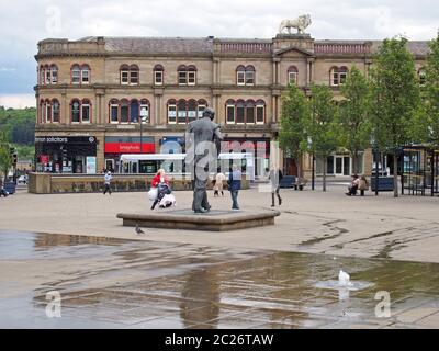 Persone che camminano in piazza st georges a Huddersfield tra le fontane d'acqua e gli edifici circostanti Foto Stock