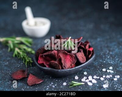 Fette di barbabietola cotte con rosmarino grossolano profumato al sale marino. Dieta vegana idea e ricetta alimentare. Sana patatine di barbabietola in casa in piastra e ingredienti su Foto Stock