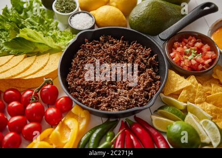 Ingredienti per Chili con carne in padella di ferro su tavolo di legno bianco Foto Stock