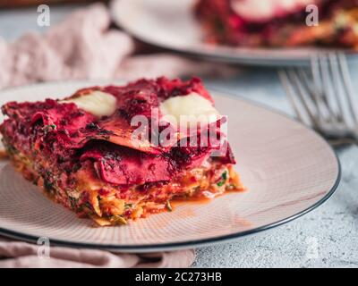 Ortaggio pranzo Rainbow lasagne sulla piastra di rosa. Idee e ricette per vegetariani sani per pranzo o cena. Lasagne con barbabietola, zucca, funghi, r Foto Stock