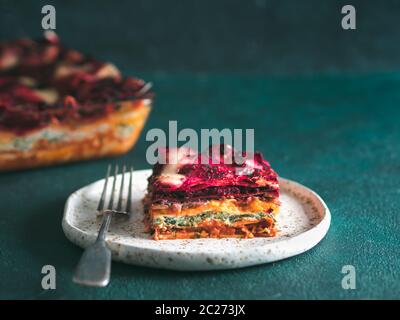 Ortaggio pranzo Rainbow lasagne su sfondo verde.idee e ricette per vegetariani sani la cena o il pranzo.Le Lasagne con le barbabietole, zucca, testa a fungo Foto Stock