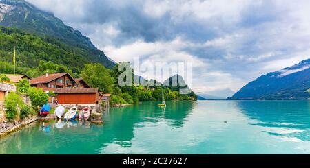 Case tradizionali in legno, barche e yacht sul lago di Brienz nel villaggio svizzero Iseltwald, Svizzera Foto Stock