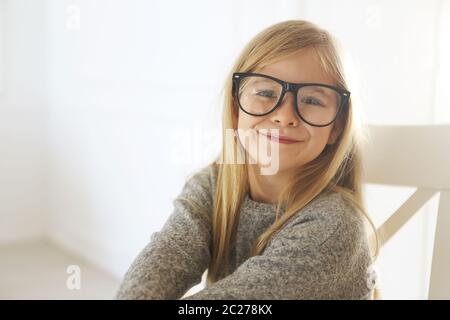 Sorridente ragazza carina con occhiali neri su sfondo bianco Foto Stock