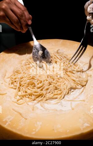 Lo chef cucinare la pasta nella ciotola di formaggio Foto Stock