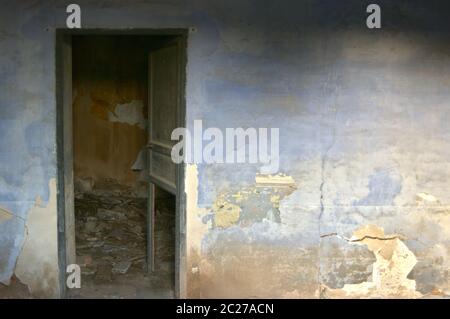 parete della stanza con vernice deteriorata e porta aperta Foto Stock