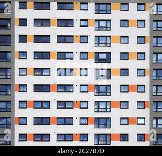 un'immagine a piena cornice di finestre in un grande ed alto edificio di appartamenti con file ripetute di finestre con pareti bianche con orang Foto Stock