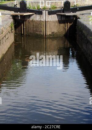 un primo piano di vecchie porte chiuse in legno sul calder e canale di navigazione hebble in brighouse riflessa nell'acqua Foto Stock