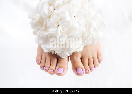 Piedi e chiocciole dopo pedicure con fiori bianchi Foto Stock