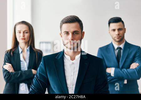 Ritratto di un bell'uomo d'affari sicuro in ufficio con il suo team sullo sfondo Foto Stock