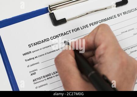 Firma di un contratto standard per la performance dal vivo di musicisti. Un musicista che riempie il contratto di performance live Foto Stock