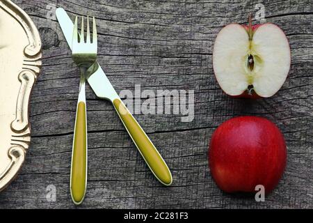 Due mezze mele, posate e piatto su un vecchio tavolo di legno Foto Stock