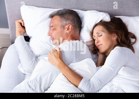 Coppia amare giovane che dorme sul letto con coltre bianca Foto Stock