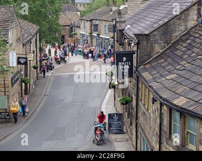 una vista aerea del centro della città di hebden bridge con le persone che camminano intorno ai negozi e che si siedono fuori un pub durante un fine settimana estivo Foto Stock