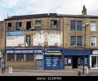 una donna cammina davanti a un negozio di articoli in delitto e una galleria di divertimenti in piazza oastler a bradford, west yorkshire Foto Stock