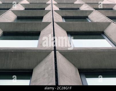 vista prospettica di finestre angolari geometriche in cemento sulla facciata di un edificio modernista in stile brutalista degli anni '60 Foto Stock