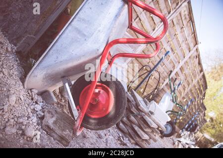 Costruzione e ristrutturazione: Primo piano di una carriola in cantiere Foto Stock