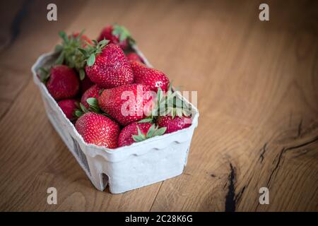 Estate: Fragole rosse fresche in tazza, tavolo in legno Foto Stock