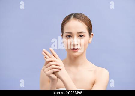 mani donna applicando crema idratante mani su viola Foto Stock