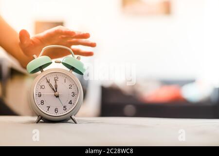 L'uomo sta premendo una sveglia al mattino, sole e sfondo sfocato Foto Stock