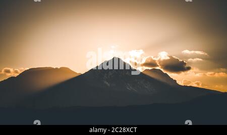 Tramonto su una montagna, fasci di luce Foto Stock