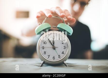 L'uomo sta premendo una sveglia al mattino, sole e sfondo sfocato Foto Stock