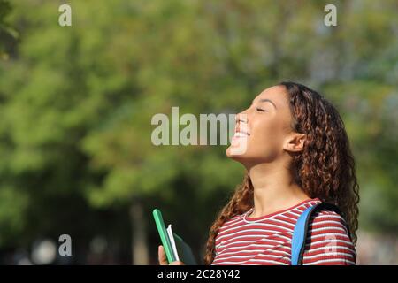 Felice razza mista studente respirare profondamente aria fresca in piedi in un parco o campus Foto Stock