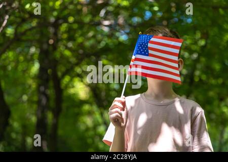 Ragazzo che rimane e prende la bandiera americana in mano. Giornata dell'indipendenza degli Stati Uniti. 4 luglio Foto Stock